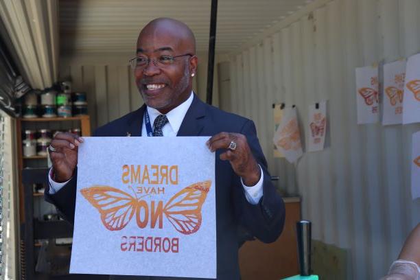 Bryan Stewart holding up a dreams have no borders poster. 